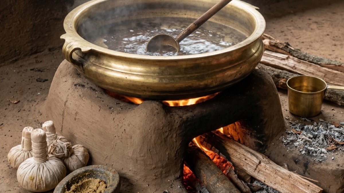 Traditional Ayurvedic medicine being prepared in a large brass vessel over a clay wood-fire stove, with herb bundles and a stone mortar nearby